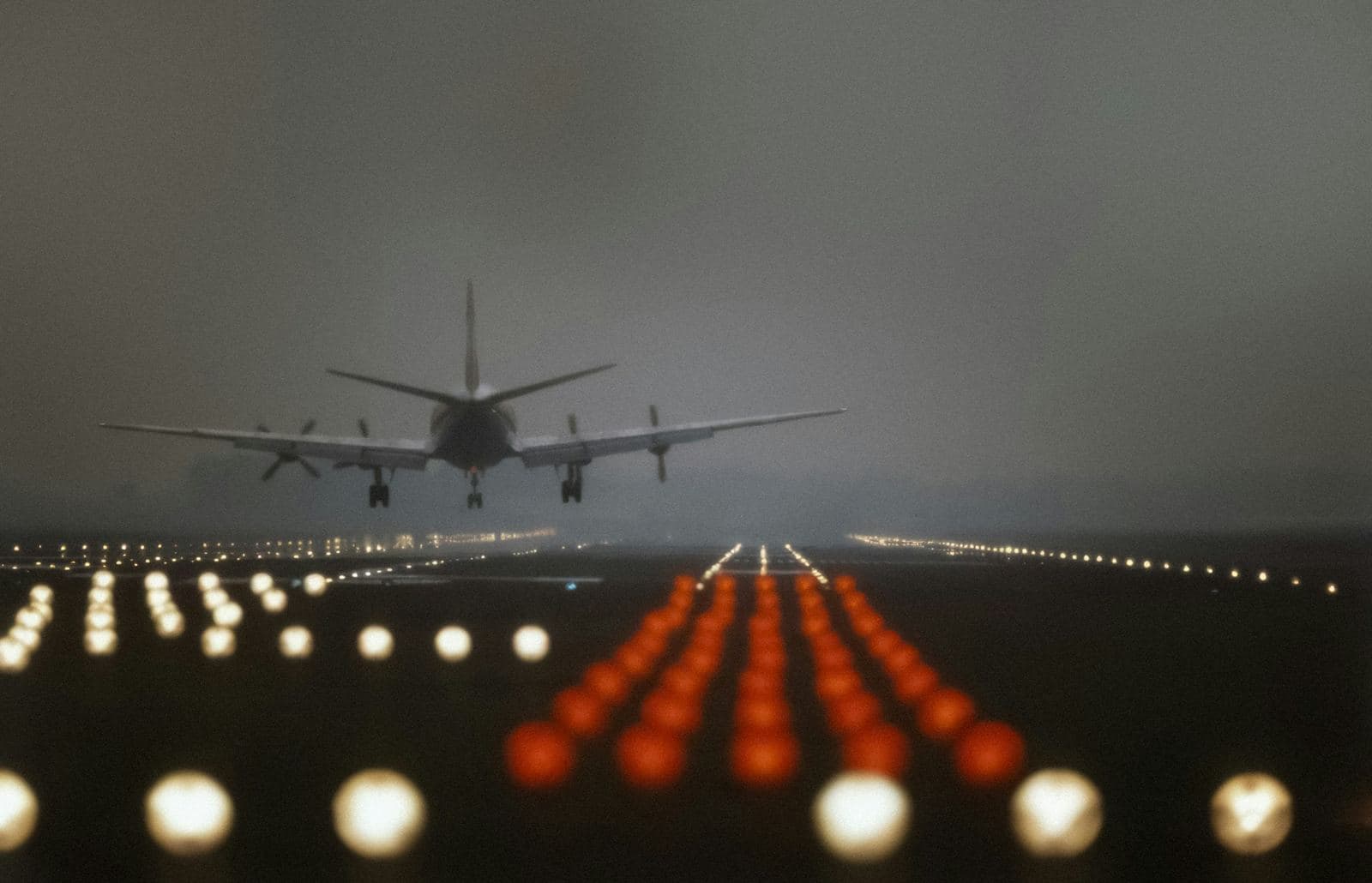 An airliner coming in to land at dusk over the runway approach lights