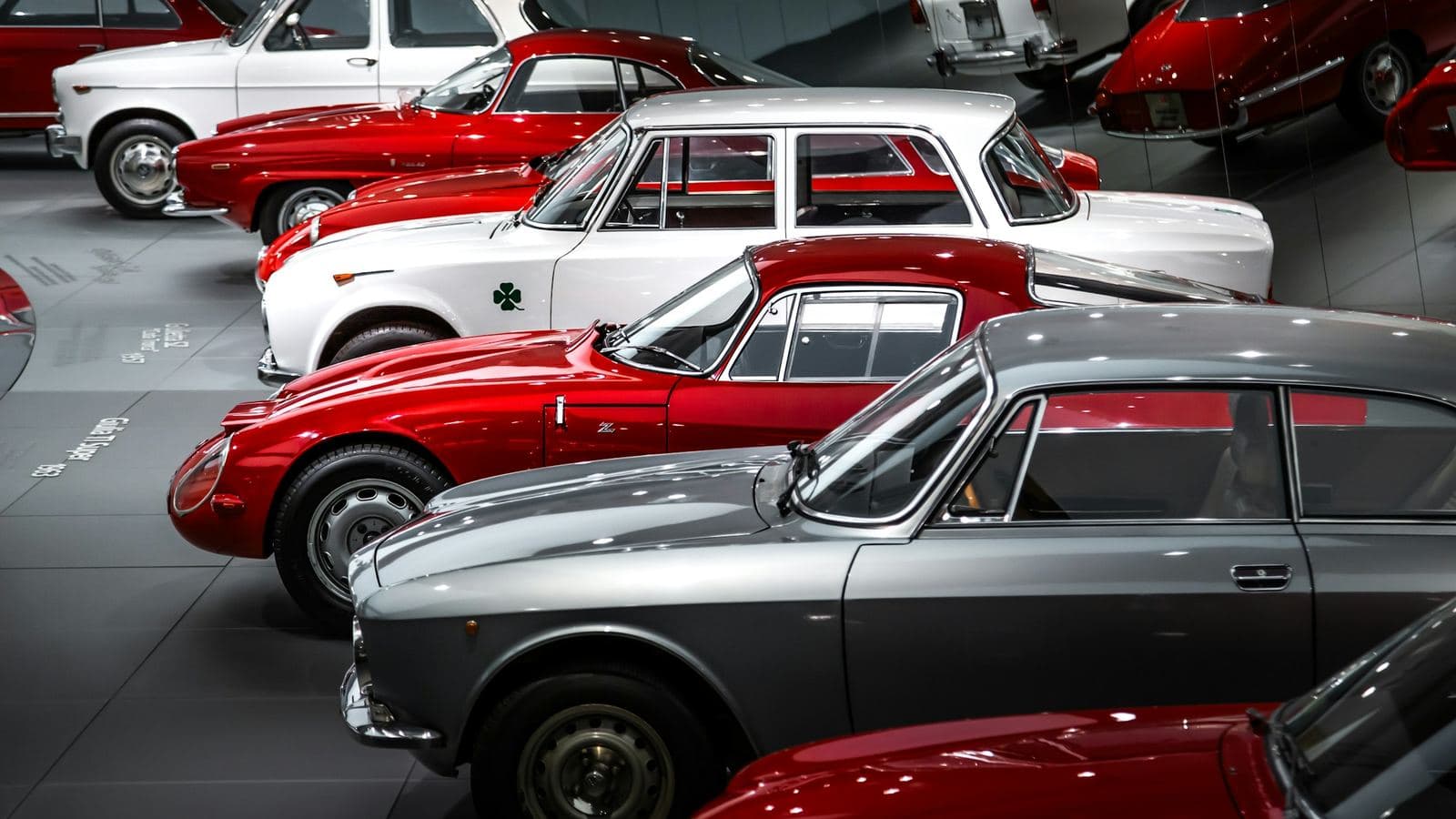 Rows of classic coupés and saloons parked close together indoors